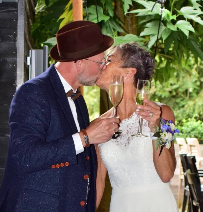 Bruidegom kust bruid onder bladeren – liefdevol moment op trouwdag