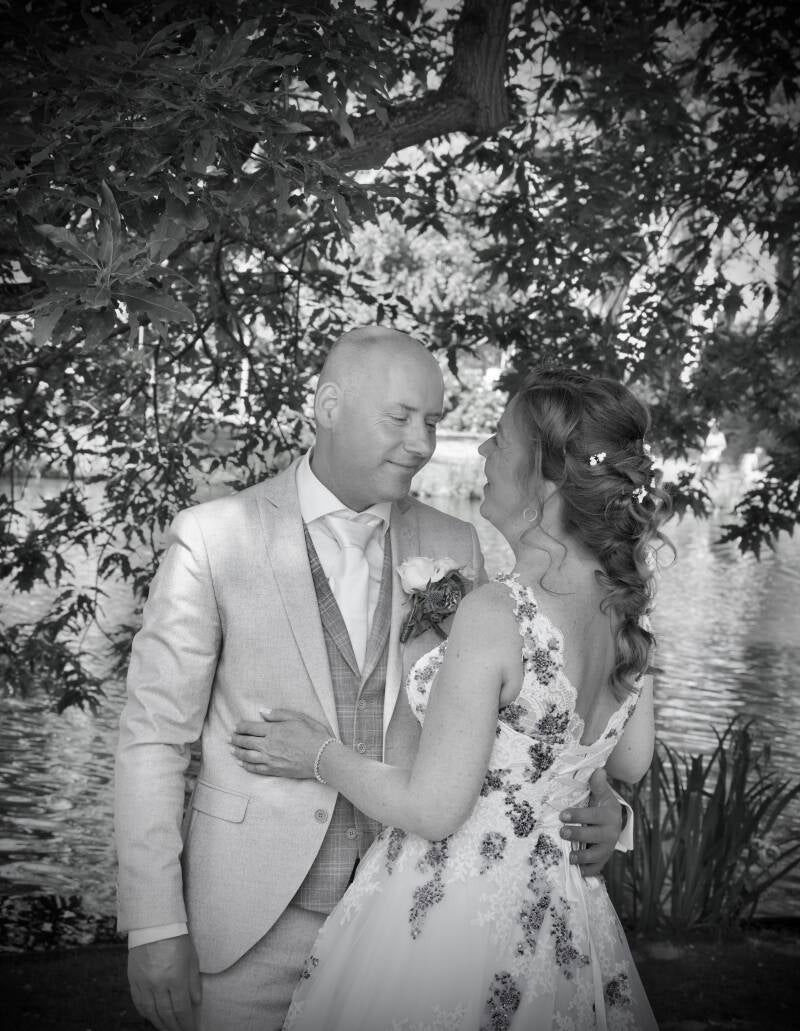 Zwart-wit portret van bruidspaar aan het water – elegante trouwfoto
