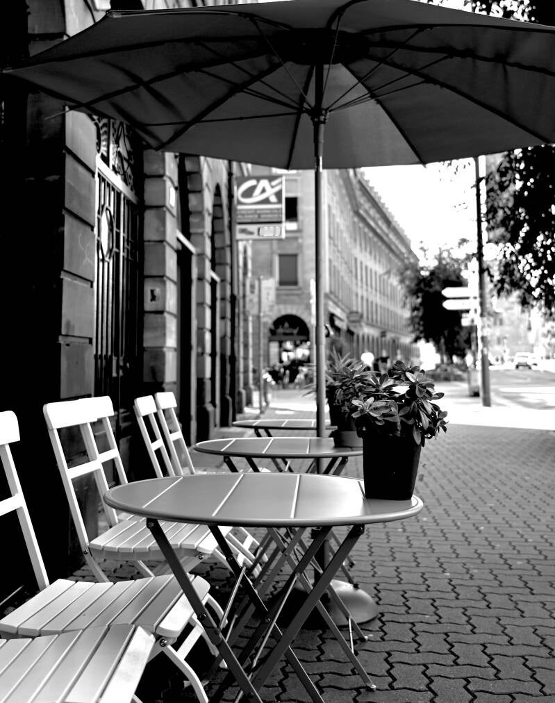 Twee stoelen en tafeltje op stoep – gezellige straat in zwart-wit