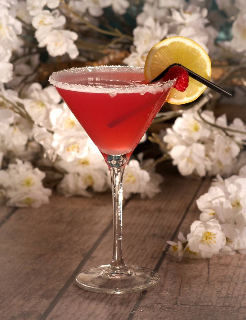 Rode cocktail met citroen op tafel met bloemen – drank- en sfeerfotografie