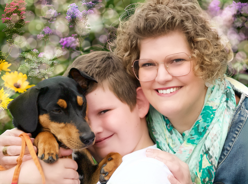 Vrouw met kind en hond in bloemenweide – liefdevol familieportret met huisdier