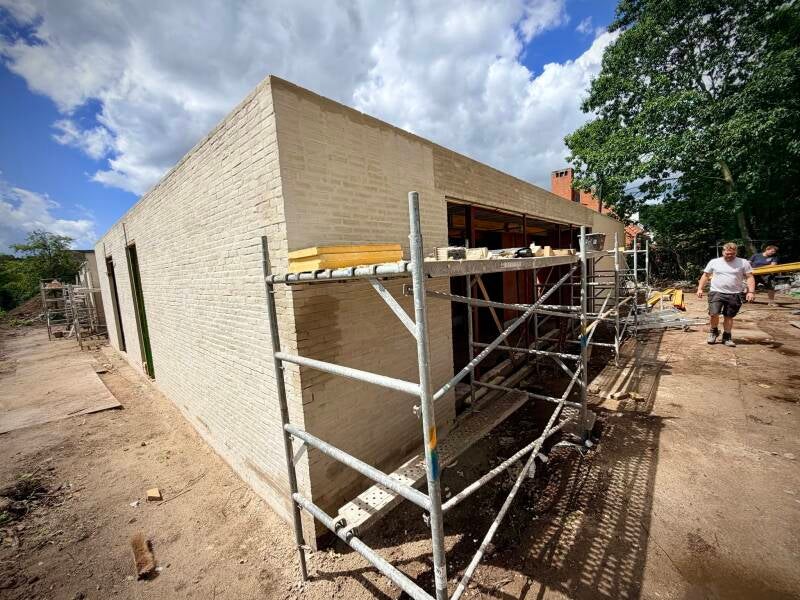 Gevelhoek in lichte baksteen met stelling en twee mensen op de werf in Varsenare.