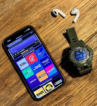 Een smartphone met draadloze oordopjes en een radioportal om radio te streamen tijdens het sporten.