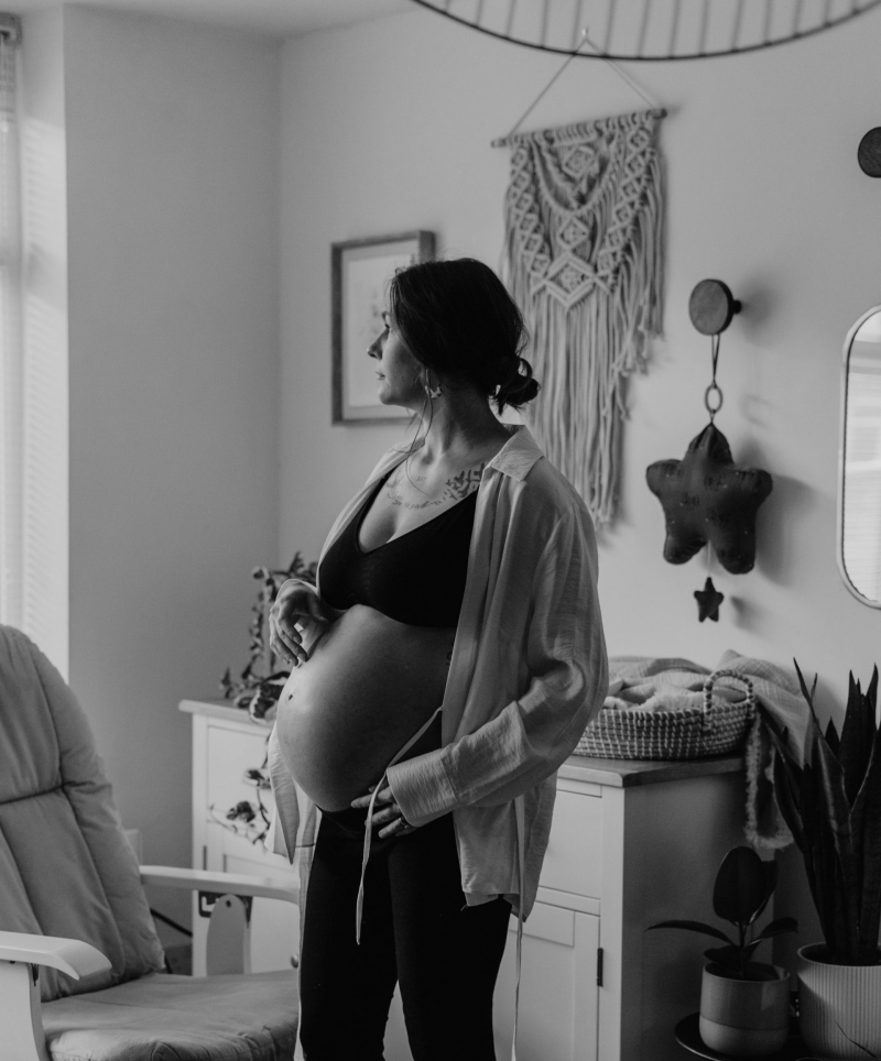 Pregnant woman standing in a cozy nursery, preparing for birth with doula support and prenatal care Rotterdam