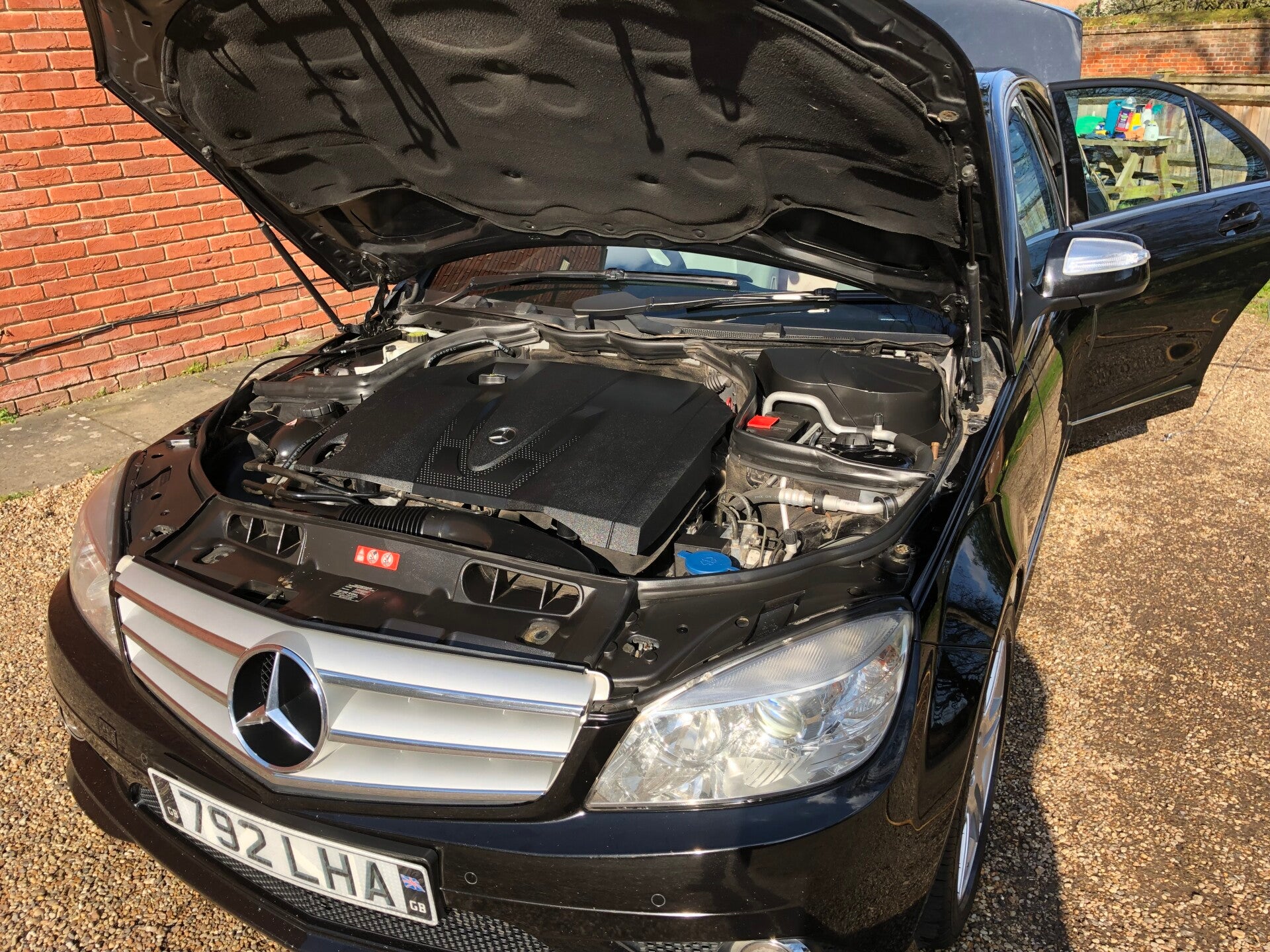 Picture of a mechanic under the bonnet of a car, looking at the engine