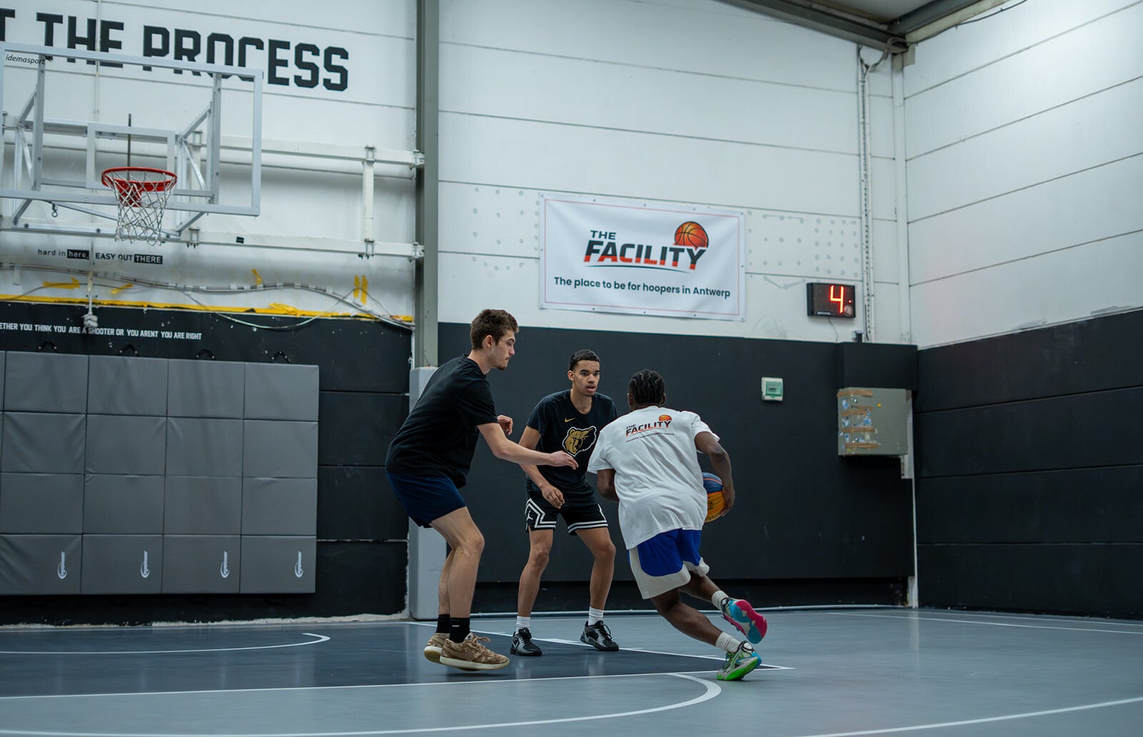 Spelers spelen 3x3 basketbal op het indoor court van The Facility Merksem met banner en scorebord