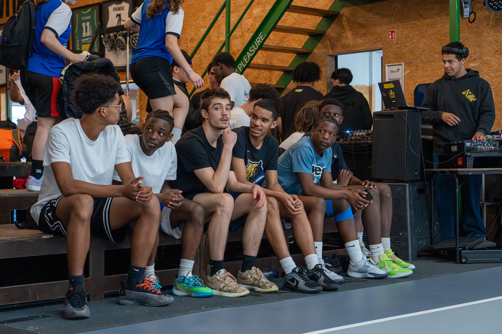 Groep jonge basketbalspelers zit op de tribune tijdens een basketbalevent in Antwerpen