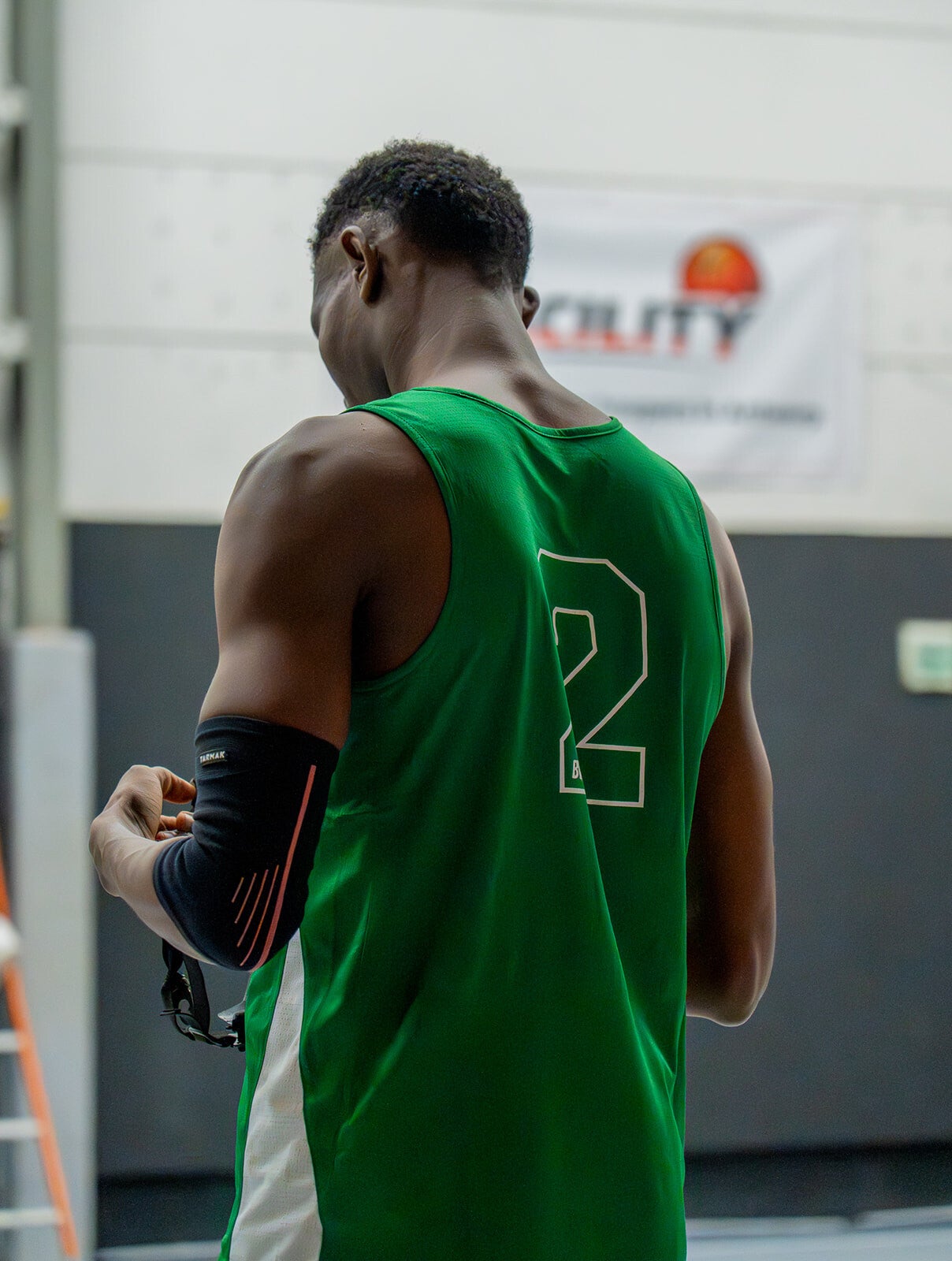 Basketbalspeler met rugnummer 2 voor de banner van The Facility Merksem Antwerpen