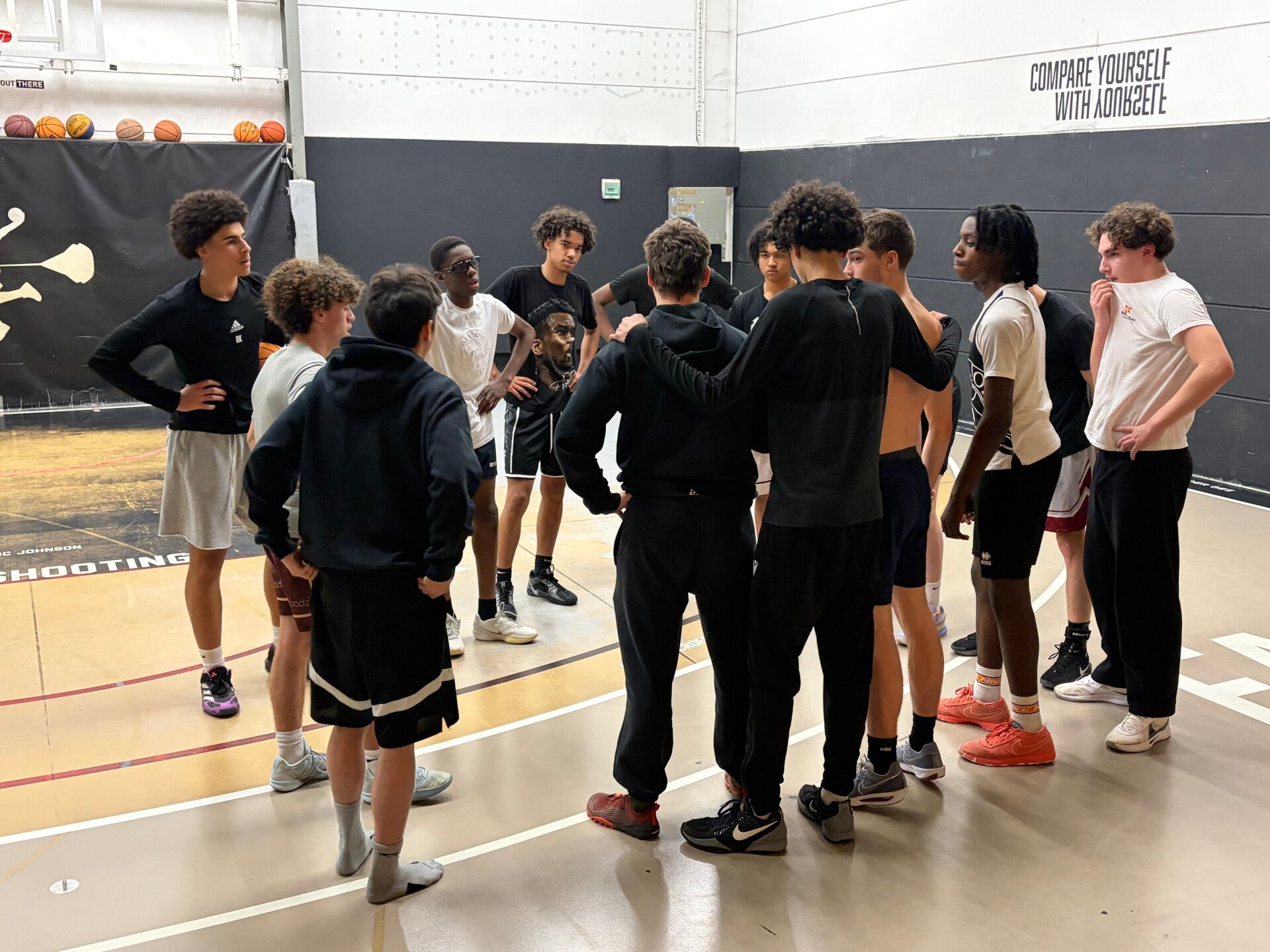 Basketbalteam luistert naar coach tijdens huddle op het indoor court van The Facility Merksem
