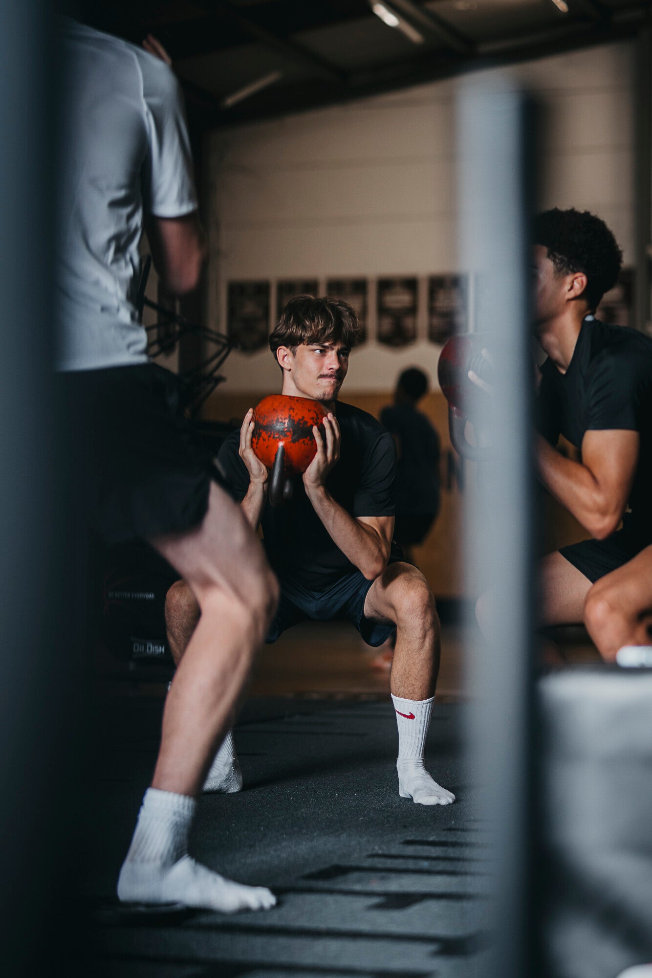 Basketbalatleet doet squat met medicijnbal tijdens krachttraining in de gym van The Facility