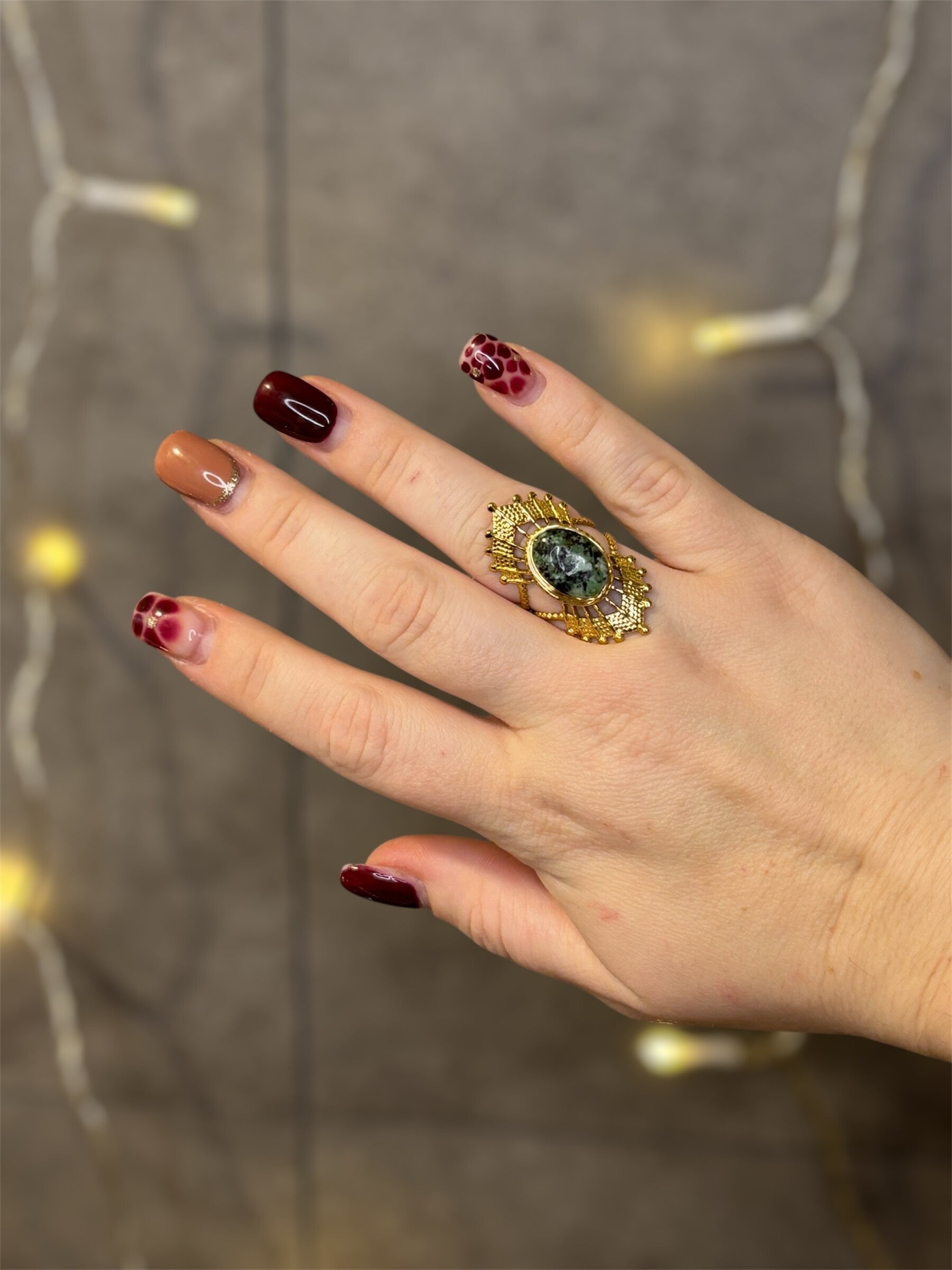 Bague dorée ajustable style solaire avec pierre ovale verte et détails ciselés