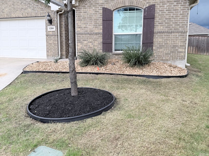 Professional landscape design with flower beds and brick edging at a Fort Worth residential property