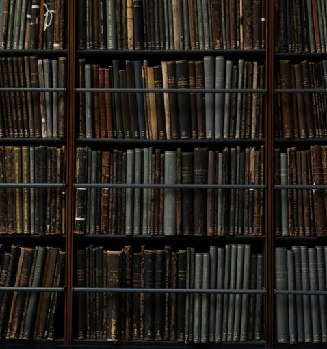 Library shelves filled with old bound volumes, representing research at The National Archives UK for military service records