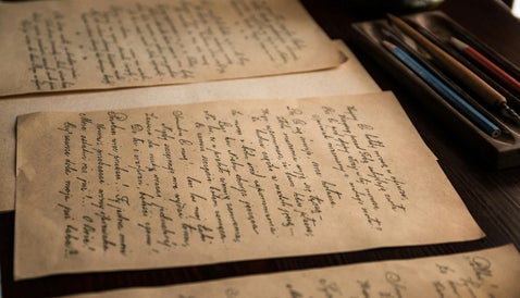 Old military-style documents and writing tools, representing personal accounts found in war diaries