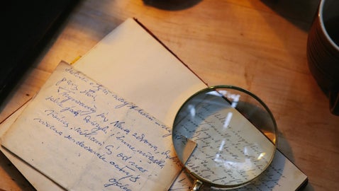 Magnifying glass over handwritten documents, symbolising the process of identifying a soldier’s regiment from wartime records