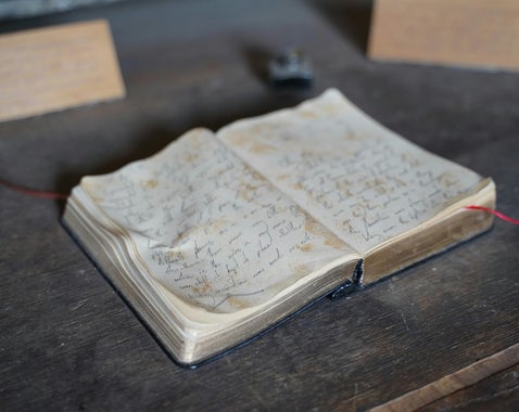 Faded journal on wooden table representing the daily entries found in a regimental war diary for military research