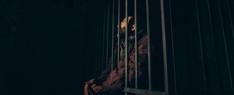 Man behind bars in low light, symbolising World War II prisoner of war records and tracing captured military ancestors