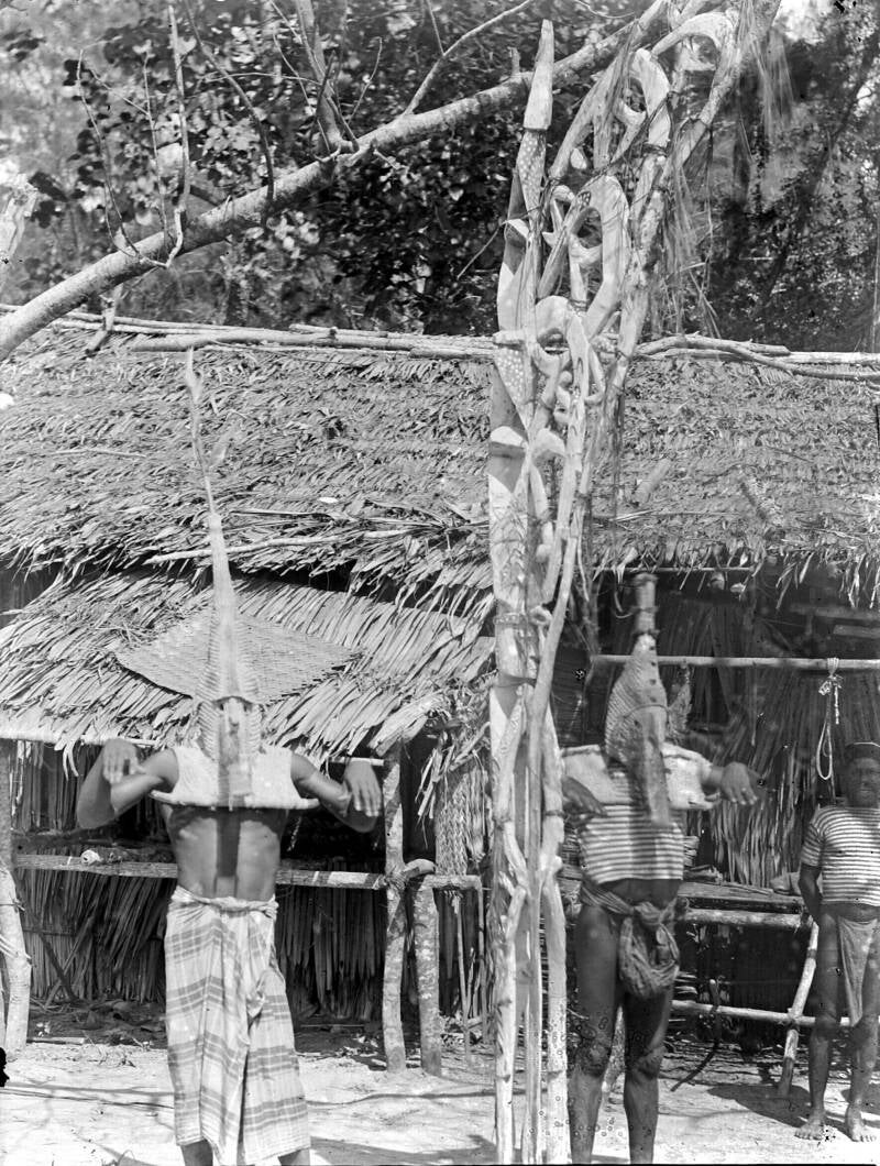 Gemaskerde mannen bij een voorouderpaal tijdens een initiatiefeest in een dorp aan de Mimikarivier 1916 TM-10008208 Kamoro