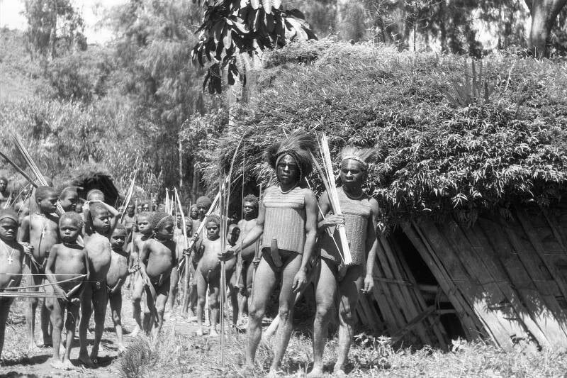 Twee gebolsterde Moni's en een groep kinderen omgeving Bilorai 1963. Negatieven IrianJaya1-19-012 