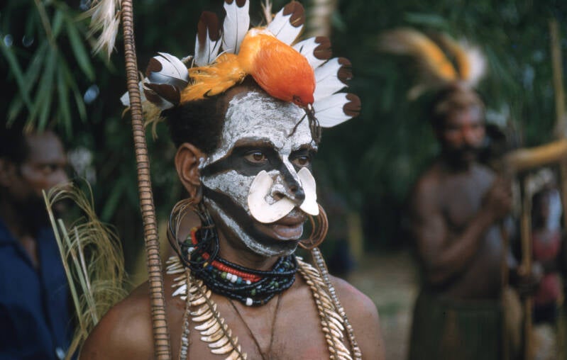 Man uit de Mappi getooid met paradijsvogel, jaarvogelveren, neusschelp en ketting van hondentanden. Piet ter Laag diapositief 209-3-086