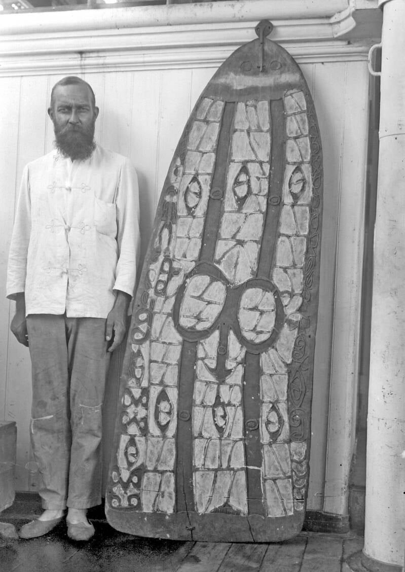 Portret van Dr HA Lorentz staande naast een Asmat-schild aan boord van het expeditieschip tijdens de Tweede Zuid-Nieuw-Guinea-expeditie TM-10010339