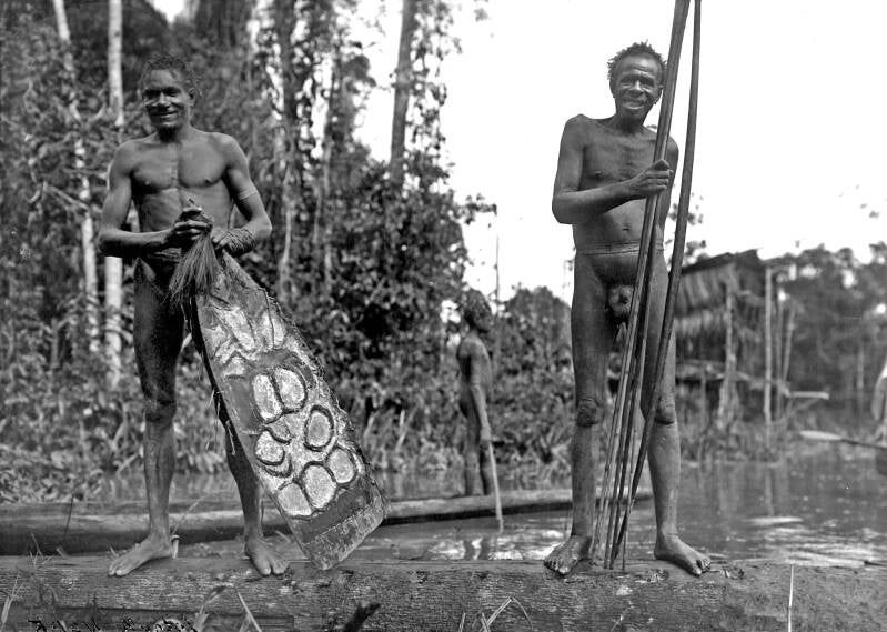 TM-10006143 Twee Asmat Papoeas met een schild en pijl en boog bij de Noord-rivier -later omgedoopt in Lorentz-rivier - tegenwoordig de rivier Unir - 1909 Hendrikus Albertus Lorentz