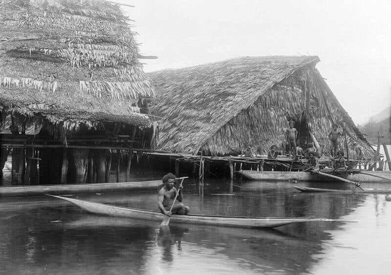TM-10010009 Papoea man in een prauw bij paalwoningen op het eiland Asei in het Sentanimeer Wichmann expeditie 1903