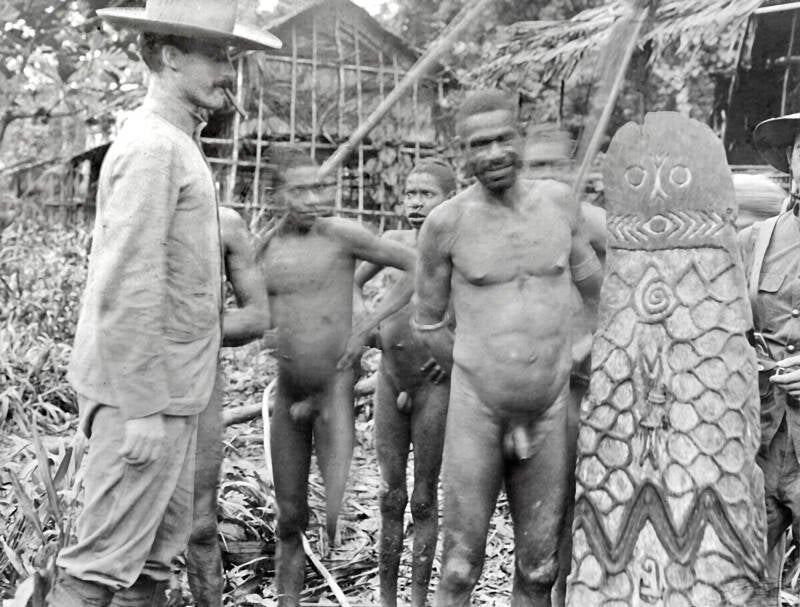 TM-60015119   Een expeditielid -Dr. Brandenhorst- bekijkt een schild van Asmat Papoeas uit een dorp langs de Noord-rivier - Unir 1908