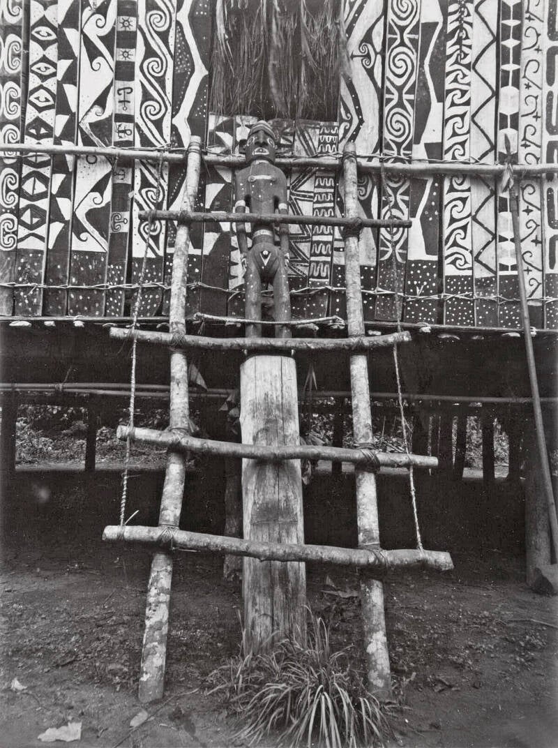 TM-60052407  Houten beeld bij de toegangstrap van een mannenhuis, Jayapura regentschap 1900-1920