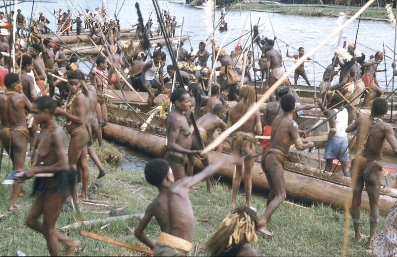 Bisj ceremonieel Sjoeroe (Sjuru; Syuru) 1956/1957 - - Asmat 38 De mannen staan nu tot hun middel in het water en proberen de boomstam de wal op te duwen Ondertussen staan zij bloot aan een bombardement van de vrouwen