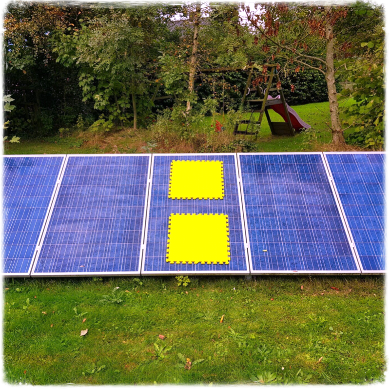 Twee gele foam tegels op een grid van 4 zonnepanelen ziet eruit als de twee puntjes van een digitale klok. Het hoort bij de GridGame Meeting, een serious game van Geck Genoeg.