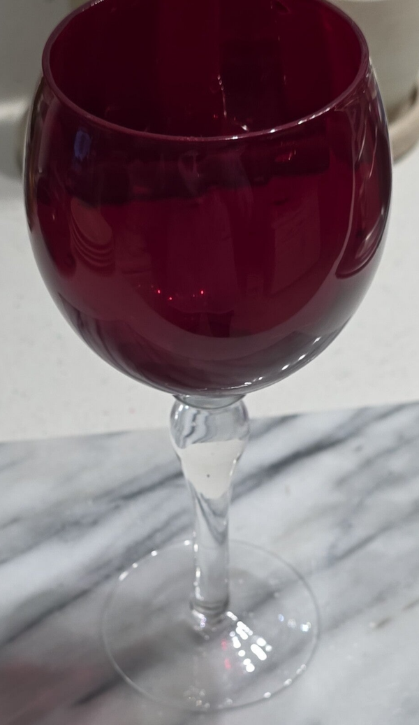A vintage hand-blown ruby red glass goblet with a twisted clear stem