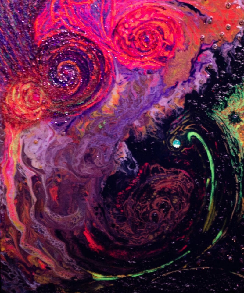 Abstract spirals of neon pink, orange and yellow hues, glowing vividly in ultraviolet light, against a dark textured background.