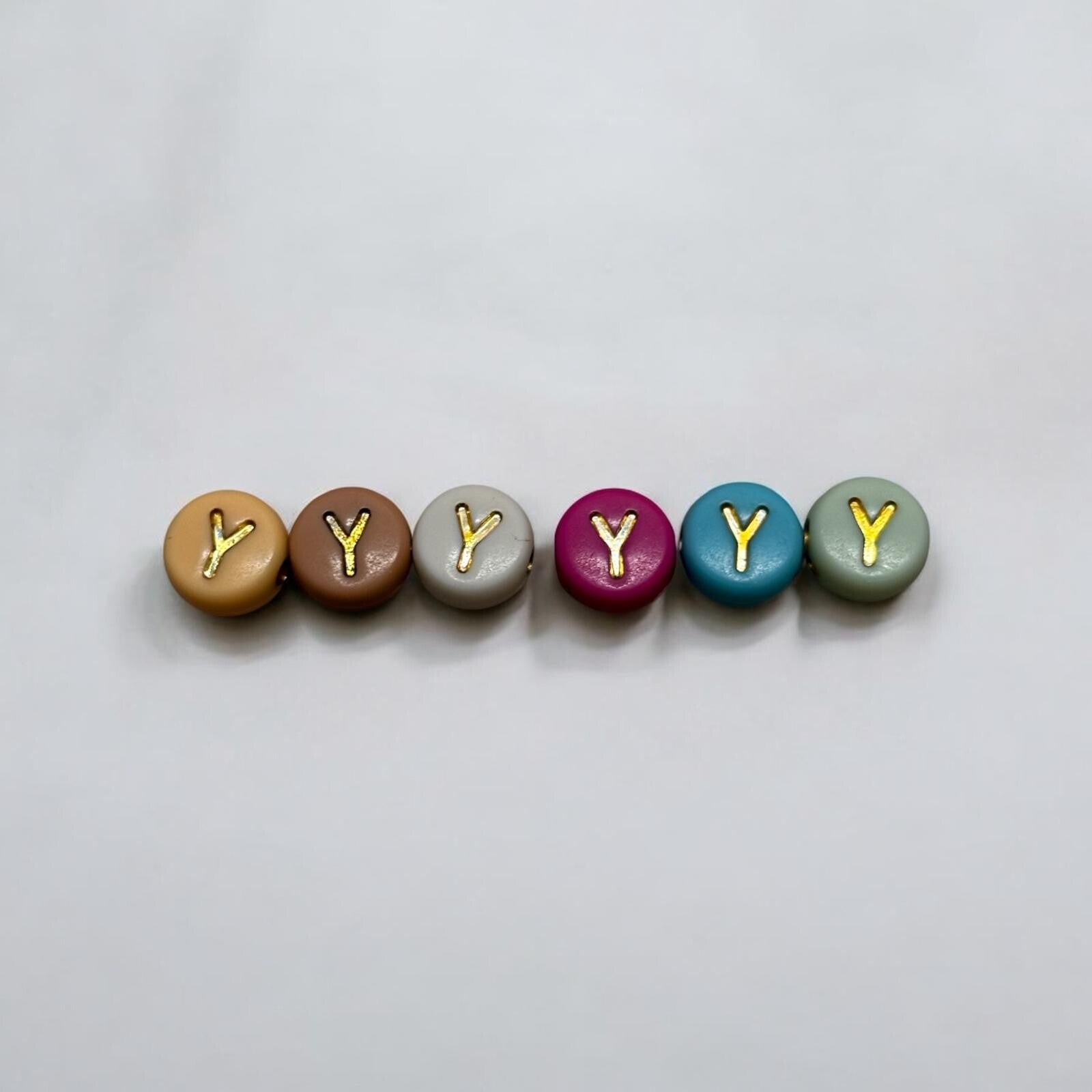 Gekleurde ronde kralen met gouden letters.