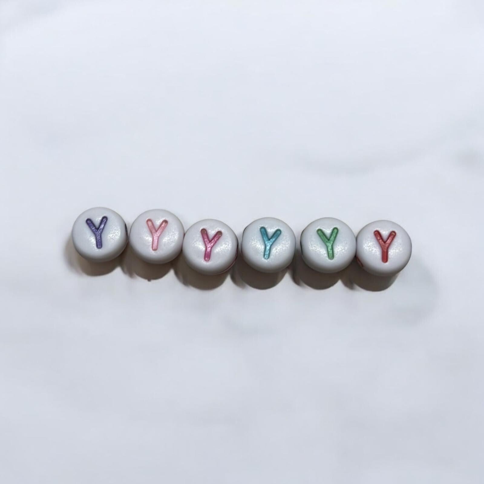 witte ronde kraal met gekleurde letters.