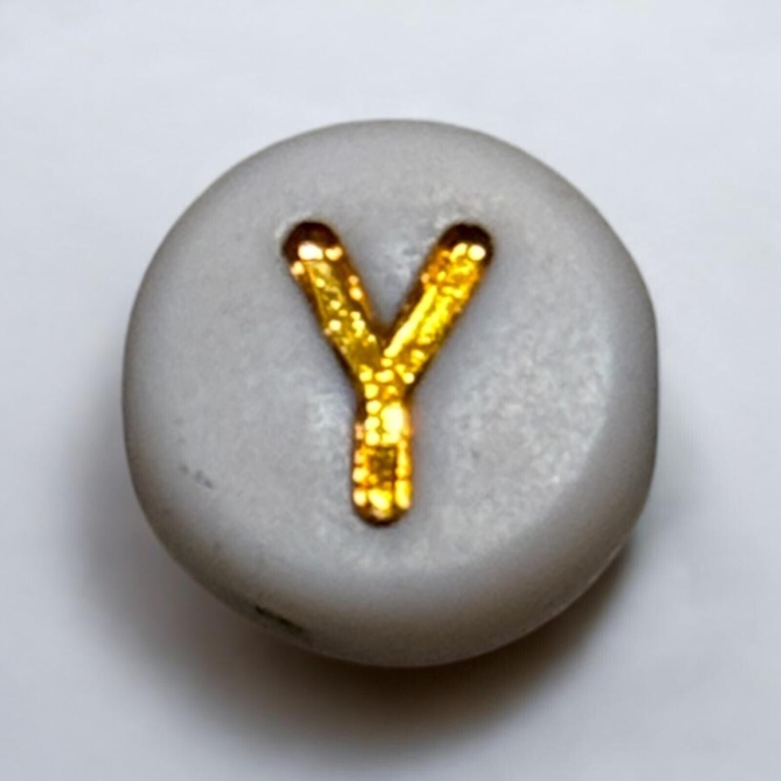 Witte ronden kraal met gouden letters.