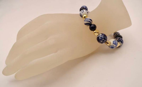 ARbl011126: Delftsblauwe armband in blauw-wit, afgewerkt met goudmetaal op elastiek.