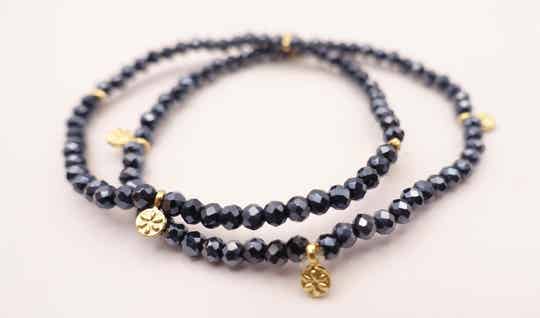 ARbl024724: Donkerblauw, heel fijn armbandje met goudmetalen bedeltjes.