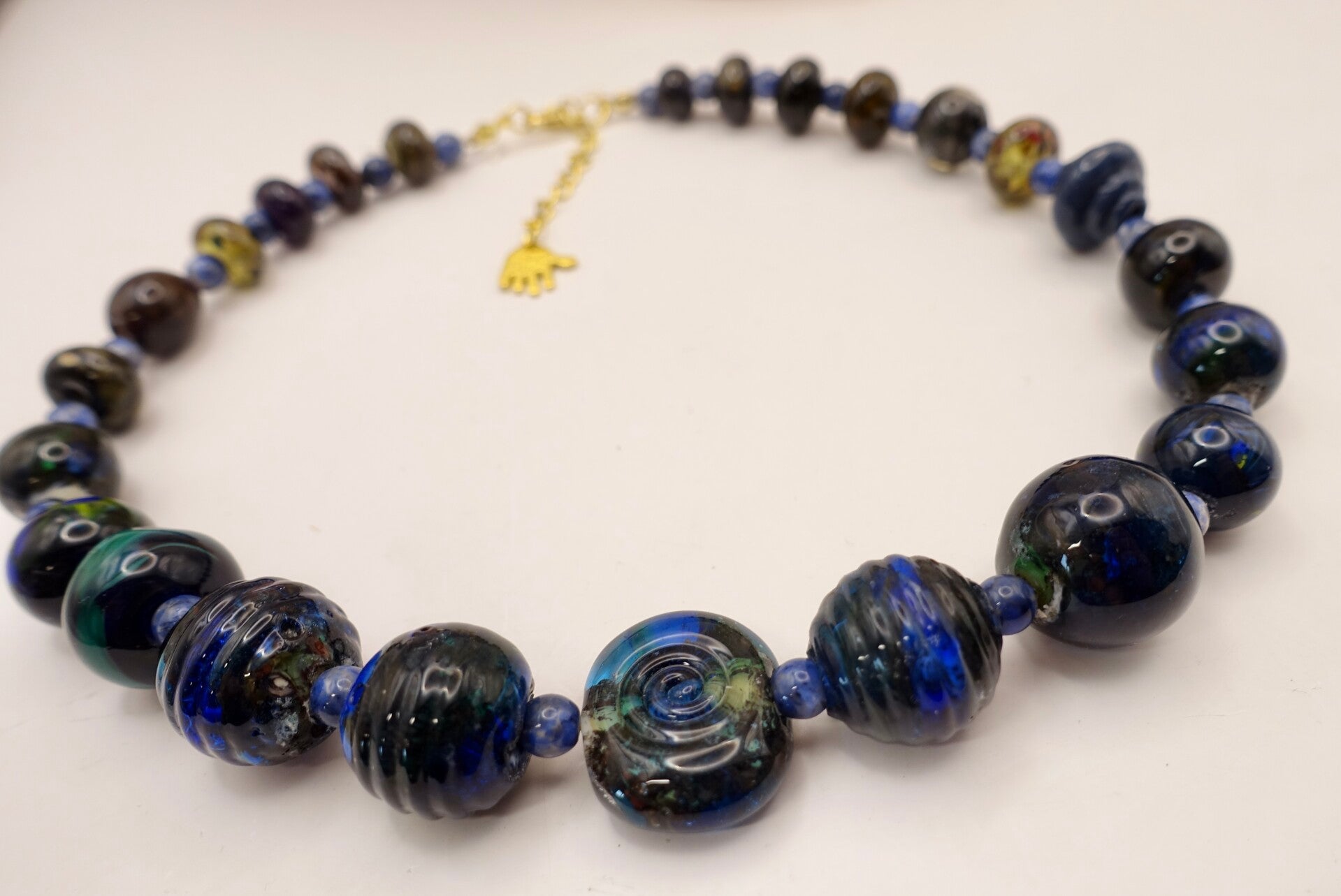 KKbl011726: Ketting in donkerblauw/groen/oker van handgemaakte kralen.