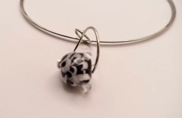 Hanzw010325: Zilvermetalen spang met zwart/witte kraal in een wisselhanger.