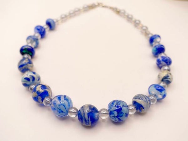 KKbl010325: Ketting van handgemaakte kralen in diverse blauwtinten.