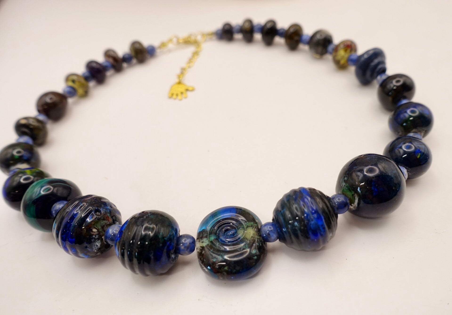 KKbl011726: Ketting in donkerblauw/groen/oker van handgemaakte kralen.