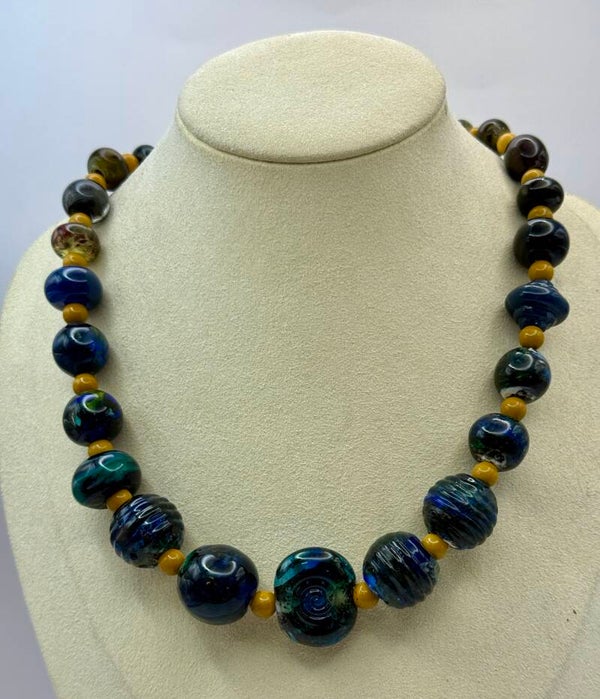 KKbl011726: Ketting in donkerblauw/groen/oker van handgemaakte kralen.