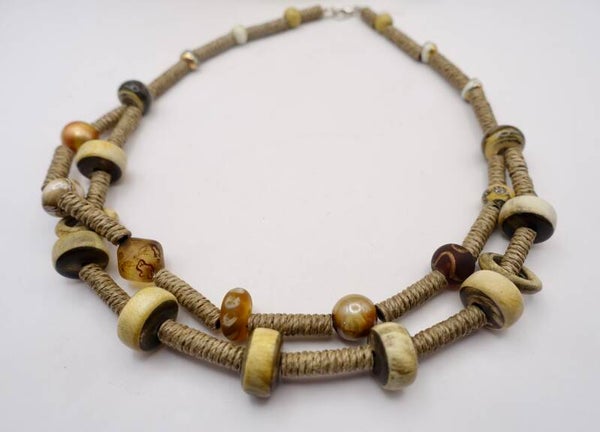 KKbr022926: Aparte ketting in naturel tinten van touw, glas, bone en houtkralen.