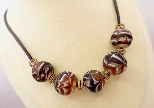 KKbr023826: Donkerbruine met iets zwart en witte ketting.