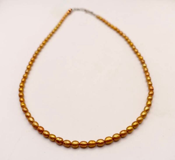 KKgo014625: Ketting van zoetwaterpareltjes in goudkleur met zilveren slotje.