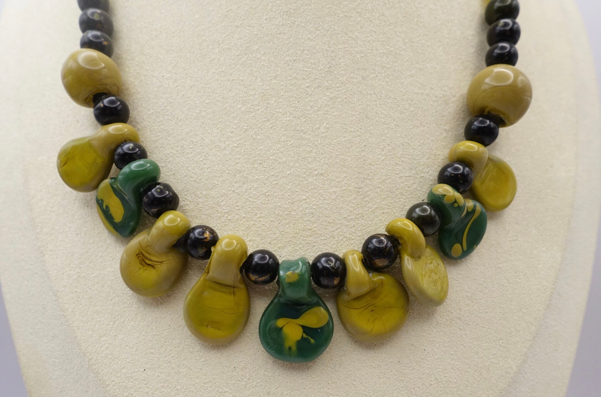 KKgr012725: Ketting in mosterd- en olijfgroen, druppelvorm.