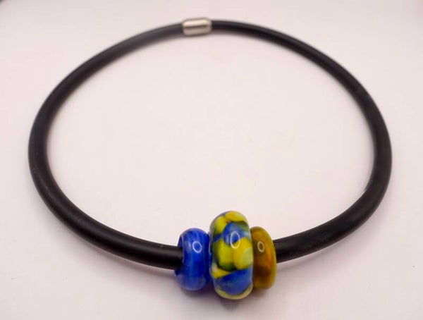 KKmix010425: Aparte ketting van dik zwart rubber met grote kralen in blauw, geel, oranje.
