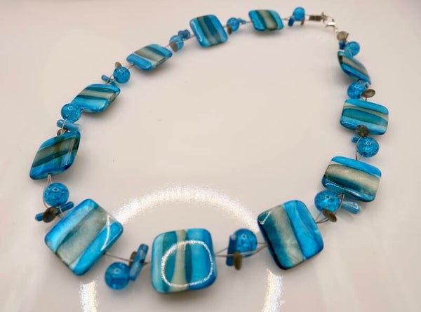 KKtu012424: Ketting van turquoise, petrol parelmoer met craquelé kralen.