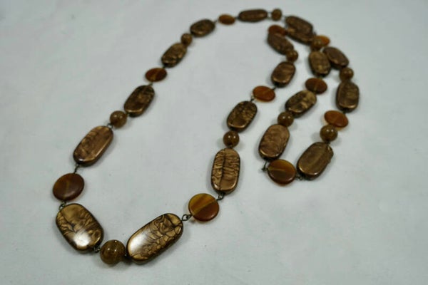 KLbr014522: Lange ketting in cognacbruin van resin en glaskralen.